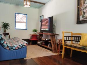 a living room with a tv and a couch and a chair at Sítio Canto da Roça Com Cachoeira in Domingos Martins