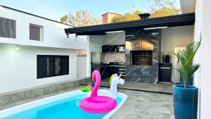 ein rosa Schwanenspielzeug in einem Swimmingpool neben einem Haus in der Unterkunft Casa Temporada Rio Quente (Em frente ao Hot Park) in Rio Quente