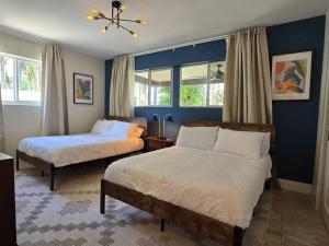 two beds in a bedroom with blue walls and windows at Palma Haus - Modern Villa with Pool Near the Beach in Hollywood Beach +37 photos