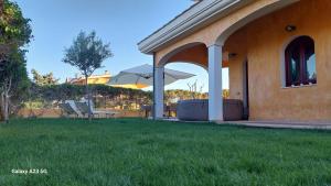 un patio con due sedie e un ombrellone in un cortile di Villa Margot-Garden & Whirpool -5 Min to the beach a Quartu SantʼElena