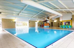 a large swimming pool with blue water in a building at Coastal Caravan Holidays - Puffin 14 in Tunstall