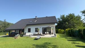 a small white house with a green yard at Pustelnika Chatka nad Brennicą in Brenna