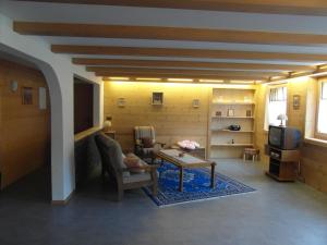 ein Wohnzimmer mit Tisch und Stühlen und einem Fernseher in der Unterkunft Les Promenades en Montagne in Chateau-d'Oex