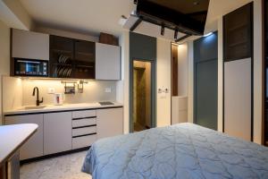 a kitchen with white cabinets and a bed in a room at Modular Central Studio in Kotor
