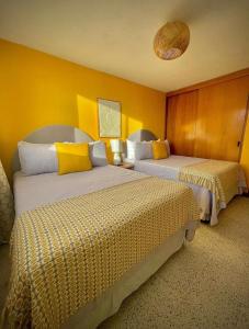 two beds in a hotel room with yellow walls at Casa 96 in Guatemala