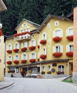 a large yellow building with flower boxes on it at Hotel Alpsu in Disentis