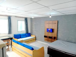 a room with two beds and a tv in it at Chalé Ubatuba pertinho do mar in Ubatuba