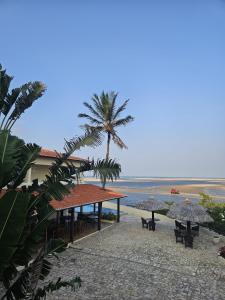 a beach with tables and umbrellas and a palm tree at Malie Hotel in Águas Belas