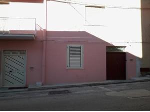 a pink building with two garage doors on a street at Adamo in Calatafimi