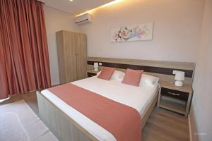 a bedroom with a large bed with red curtains at Hotel Star in Sarandë