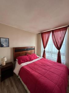 トメにあるTomé, Departamento vista al mar, playa Bellavistaのベッドルーム1室(赤いシーツと窓付きの大型ベッド1台付)