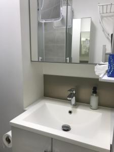 Un lavabo blanco en un baño con espejo. en 1 Next To Paris, en Montreuil