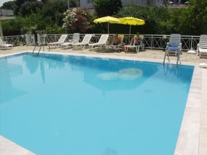 a large blue swimming pool with people sitting under an umbrella at Dimitra Apartments G in Gouvia