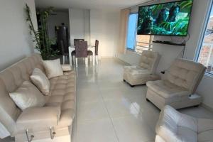 a living room with white furniture and a flat screen tv at apto 5 estrellas in Marinita