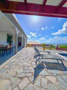 eine Terrasse mit einem Tisch und Stühlen auf einem Steinboden in der Unterkunft Villa Corail in Rivière-Salée