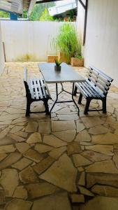 a table and two benches on a stone patio at Sermie T4 à kourou avec piscine in Kourou