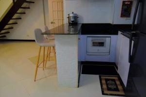 a kitchen with a counter with a stove and chairs at The Loft Nook - 2 bedrooms only in Pusok +3 photos