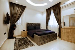 a bedroom with a large bed and a dresser at Elite Luxury 3-bedroom Apartment in Abuja in Abuja