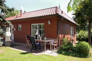 ein kleines Haus mit einem Tisch und Stühlen im Hof in der Unterkunft Feriendomizil Hönow in Hoppegarten