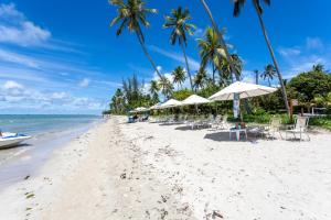a beach with chairs and umbrellas and the ocean at Eco Resort Praia Dos Carneiros - Vizinho a Igrejinha in Praia dos Carneiros