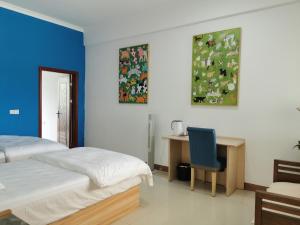 um quarto com uma cama e uma escrivaninha com uma cadeira em 小红马民宿 em Yinzhan'ao