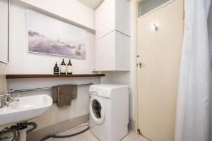 a white bathroom with a washing machine and a sink at Ocean Breezes in Fremantle +3 photos