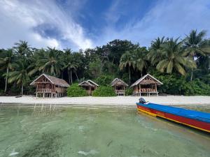 a boat in the water next to a beach with huts at Amfriwen Homestay in Yennanas Besir