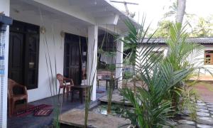 un porche de una casa con una mesa y una silla en Riverside Lal Homestay en Sigiriya