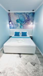 a bedroom with a large white bed with blue walls at Квартиры на Арбате 2 комнатные in Shymkent