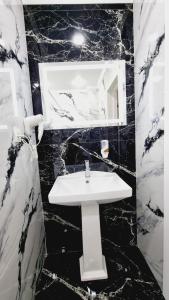 a black and white bathroom with a sink and a mirror at Квартиры на Арбате 2 комнатные in Shymkent
