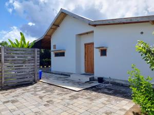 a white house with a wooden door and a fence at Happy home in Huu