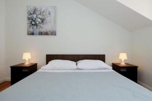 a bedroom with a large bed with two lamps on tables at Penthouse mit Balkon für fünf Personen in Bibinje