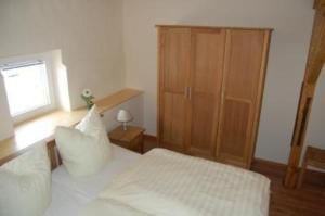 a bedroom with a white bed and a wooden cabinet at Ferienhaus Alleenwiesen in Gerswalde