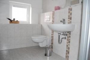 a white bathroom with a toilet and a sink at Ferienhaus Alleenwiesen in Gerswalde