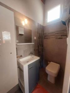 un bagno con lavandino, WC e finestra di Studio terrasse climatisé VUE MER avec parking a Cardo