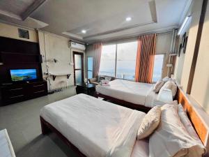 a hotel room with two beds and a flat screen tv at Aizawl Guest House in Āīzawl
