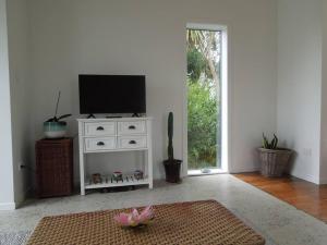 a living room with a tv on a white dresser at Raglan, walk to harbour and town, garden views in Raglan