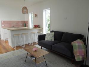 a living room with a black couch and a kitchen at Raglan, walk to harbour and town, garden views in Raglan