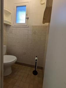 ein Badezimmer mit Toilette und Fenster in der Unterkunft Maison de vacances 400 m de la plage et du port de la Turballe in La Turballe