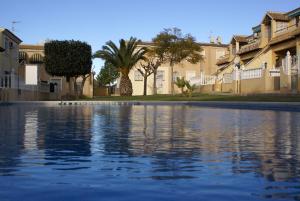 una piscina de agua frente a algunas casas en Bungalow Lomas Del Golf, en San Miguel de Salinas