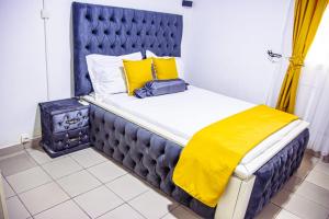 una cama con cabecera azul y almohadas amarillas en Bonamoussadi Gardens - Piscine-Wifi- Eau- Electricite 24h sur 24, en Douala 66 fotos más