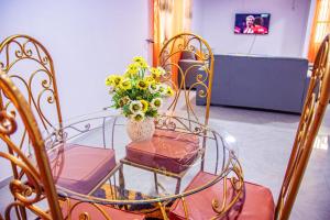 una mesa de cristal con un jarrón de flores. en Bonamoussadi Gardens - Piscine-Wifi- Eau- Electricite 24h sur 24, en Douala