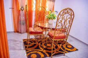 a dining room with a glass table and two chairs at Bonamoussadi Gardens - Piscine-Wifi- Eau- Electricite 24h sur 24 in Douala