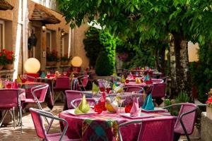 un restaurante al aire libre con mesas y sillas con manteles coloridos en Hostellerie Belle Rive en Gagnac-sur-Cère