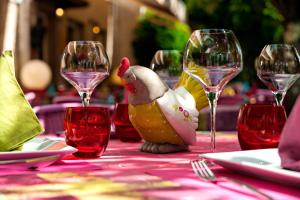 uma mesa com copos de vinho e uma galinha de brinquedo. em Hostellerie Belle Rive em Gagnac-sur-Cère