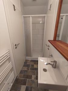 a white bathroom with a sink and a shower at Weit draußen und doch mittendrin im Apartment in Thedinghausen