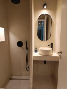 Un baño con un lavabo y un espejo en la pared. en Syros Experience - Smart Suite, en Ermoupoli