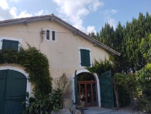 a white house with green doors and a gate at gite Pedelucq in Pouillon