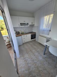 a small kitchen with white cabinets and a table at Karmen in Kampor