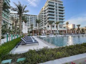 a pool with chairs and an umbrella next to a building at Address Beach Resort Residence Bahrain in Rayyā